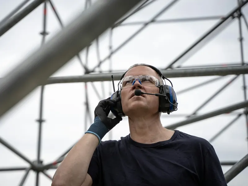 Sur une structure en acier, un monteur répond à un appel avec son casque.