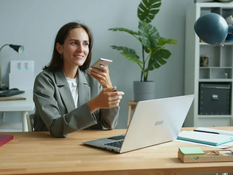 Une femme parle au téléphone à son bureau, devant son ordinateur.